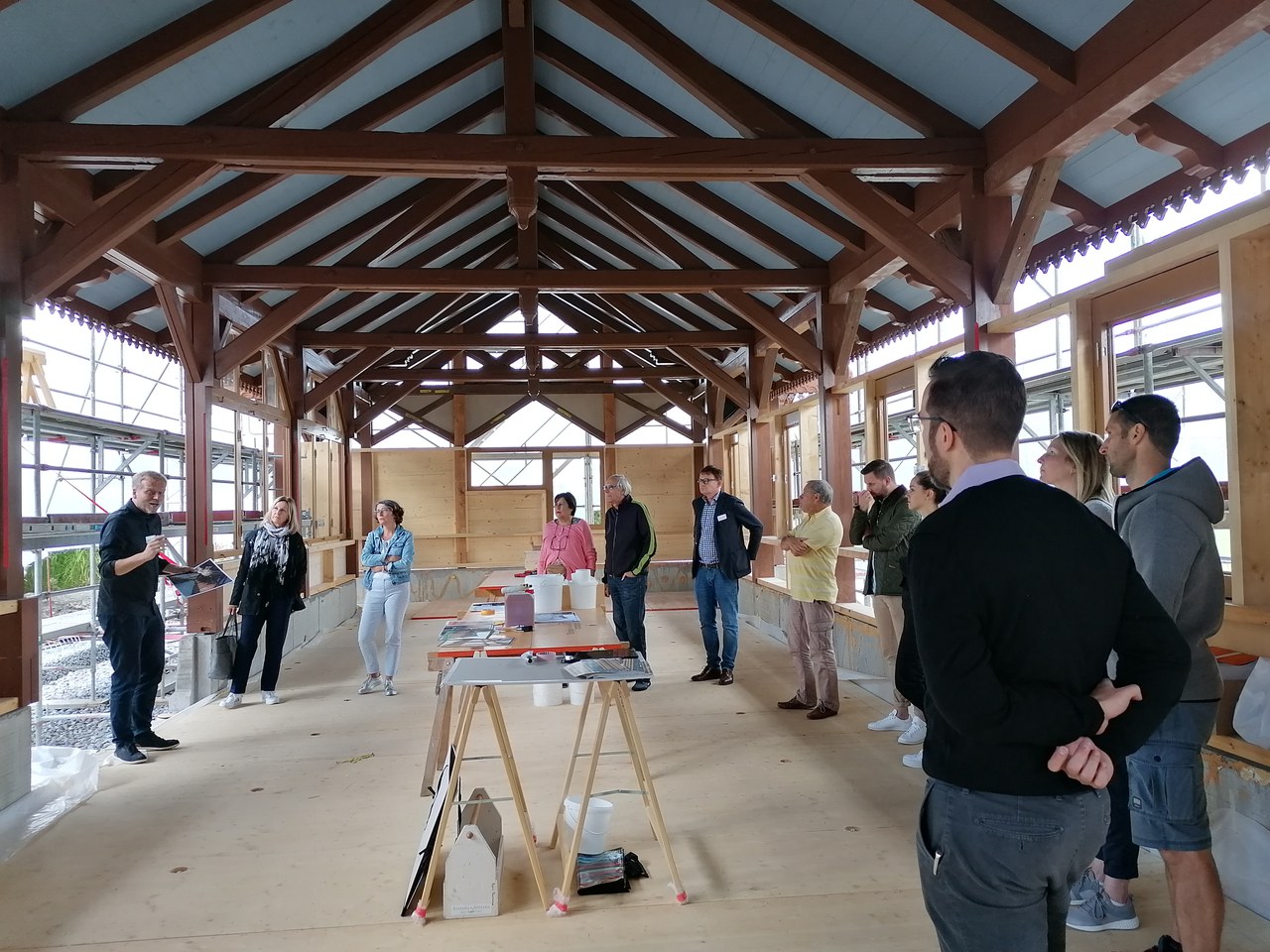 Gruppe um den Tisch stehend, Architekt Thomas Baggenstos beim Vortrag