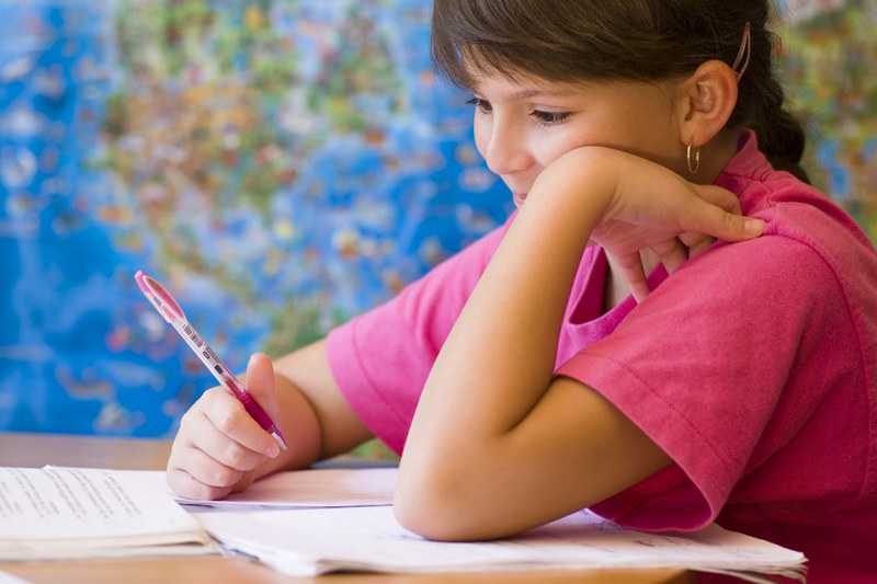 Mädchen mit Schreibstift in der Hand den Kopf aufstützend