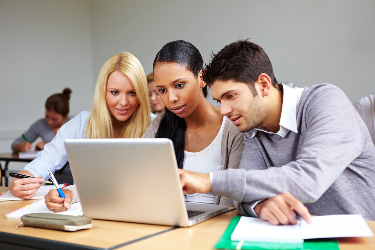 3 Schüler sitzen vor einem Laptop.