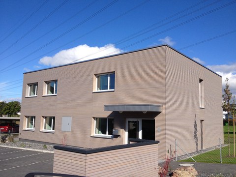 Das Foto zeigt die Sicht auf das neue Lüssihaus an der Zugerstrasse. Einen zweistöckigen Kubus mit Holzlattenfront.